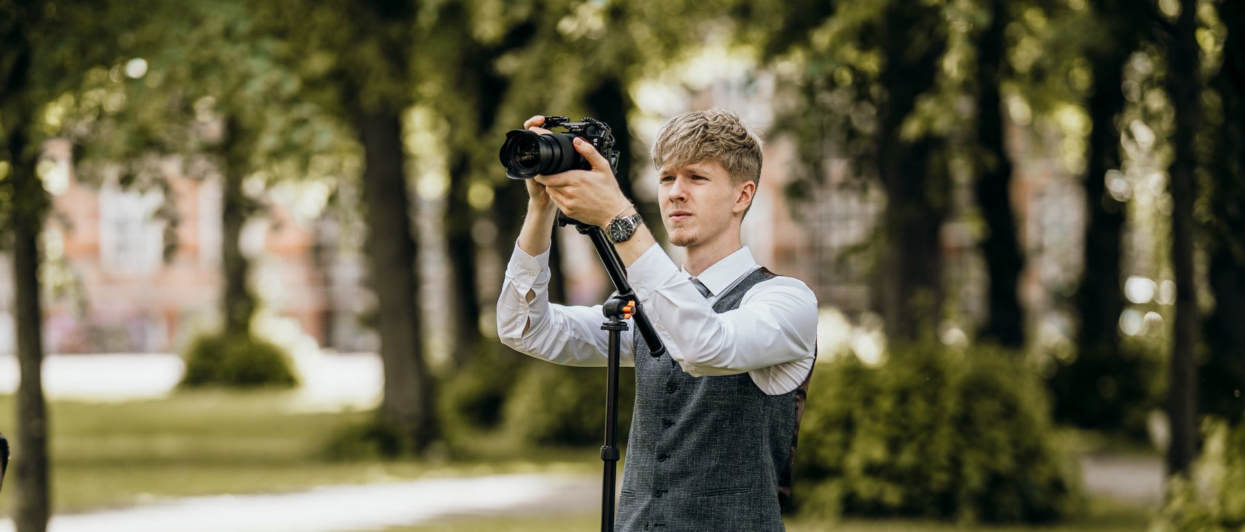 Oscar Kamps filmt eine freie Trauung im Park mit Kamera auf dem Stativ